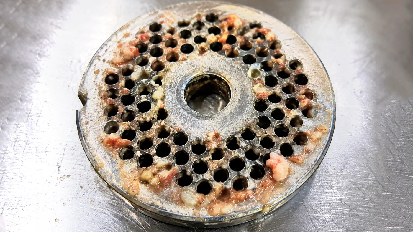 Mincer hole plate with meat and fat packed into the holes